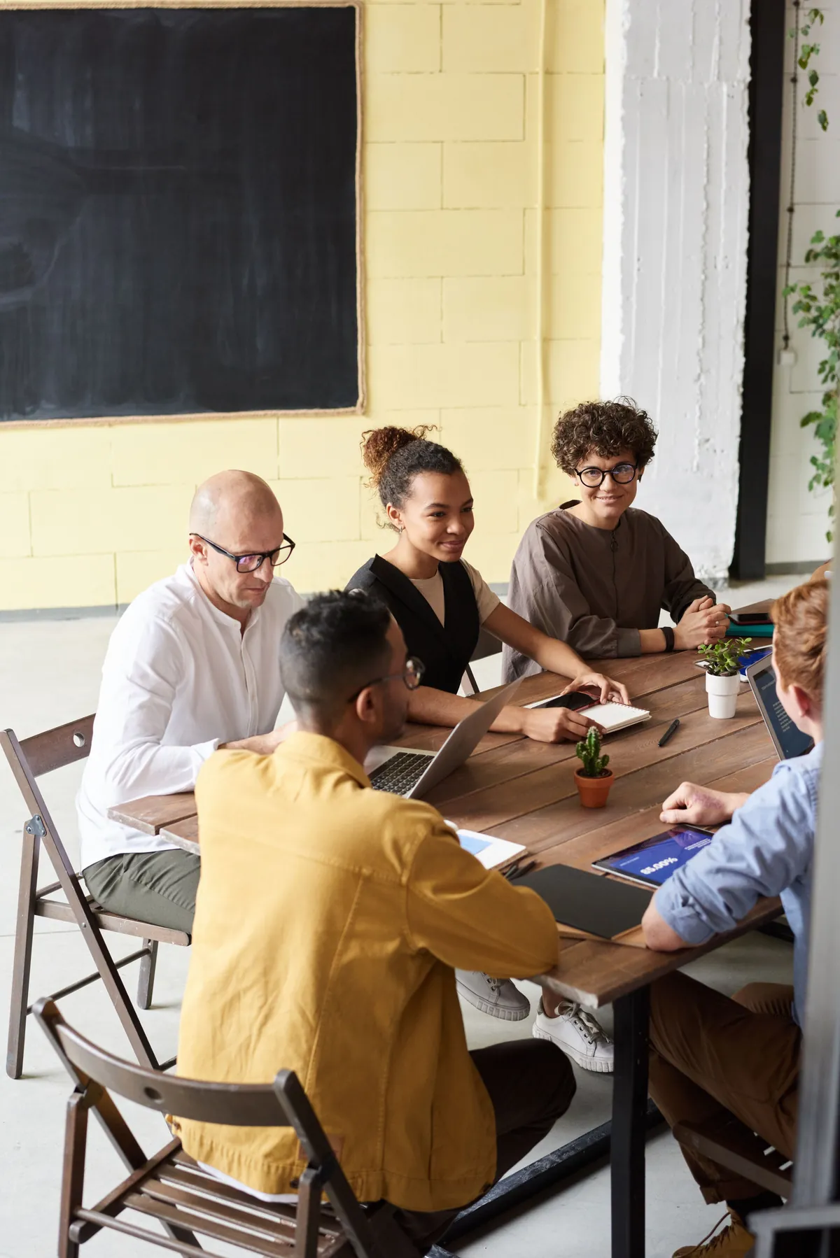People meeting around a wooden table with laptops